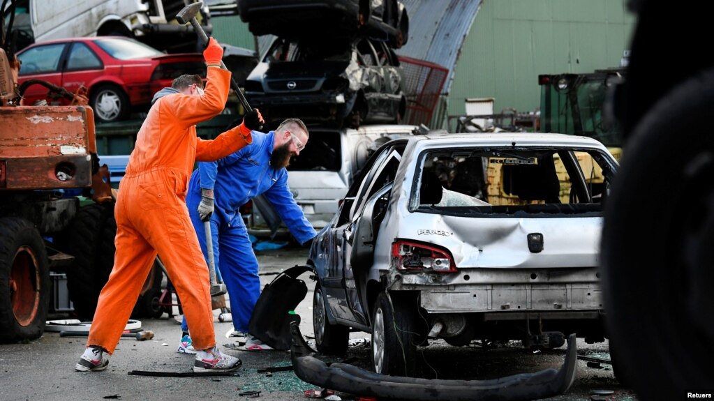 Twin brothers Steven and Brian Krijger use hammers to scrap a car to express their frustration as the Netherlands undergoes another lockdown in Vijfhuizen, Netherlands January 5, 2022. Picture taken January 5, 2022. (REUTERS/Piroschka van de Wouw)