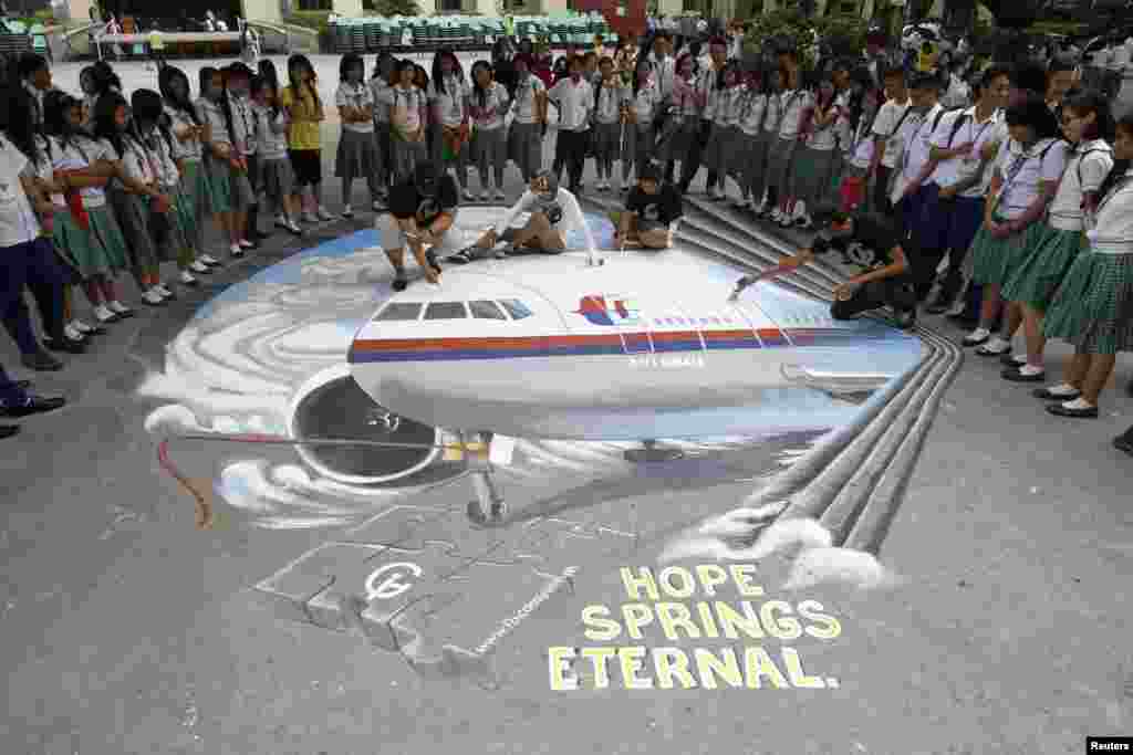Một nhóm các nghệ sĩ hoàn thành một tác phẩm về chuyến bay MH370 bị mất tích tại sân trường ở thành phố Makati, Philippines, ngày 17/3/2014.