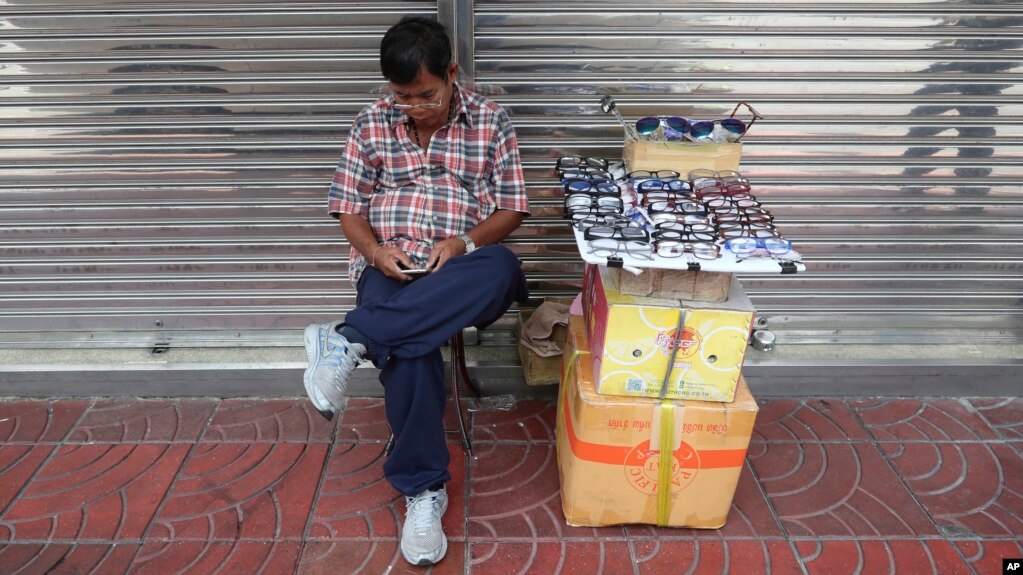 Một người Thái Lan bán kính đeo mắt xem điện thoại di động ở Bangkok, Thái Lan, ngày 28/8/2019. 