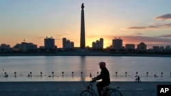 In this Saturday, Oct. 27, 2018 photo, a man rides his electric bike as the Tower of the Juche Idea is silhouetted agains the sunrise in Pyongyang, North Korea. (AP Photo/Dita Alangkara)