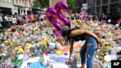 Seorang perempuan muda melihat bunga-bunga yang diletakkan di lapangan St Ann, Manchester, Inggris, 25 Mei 2017, untuk mengenang para korban ledakan seudai konser bintang pop AS, Ariana Grande di kota itu. (AP Photo/Rui Vieira).