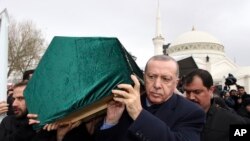 Turkey's President Recep Tayyip Erdogan, center, carries a coffin as he joins hundreds of mourners who attend the funeral prayers for nine members of Alemdar family killed in a collapsed apartment building, in Istanbul, Saturday, Feb. 9, 2019.