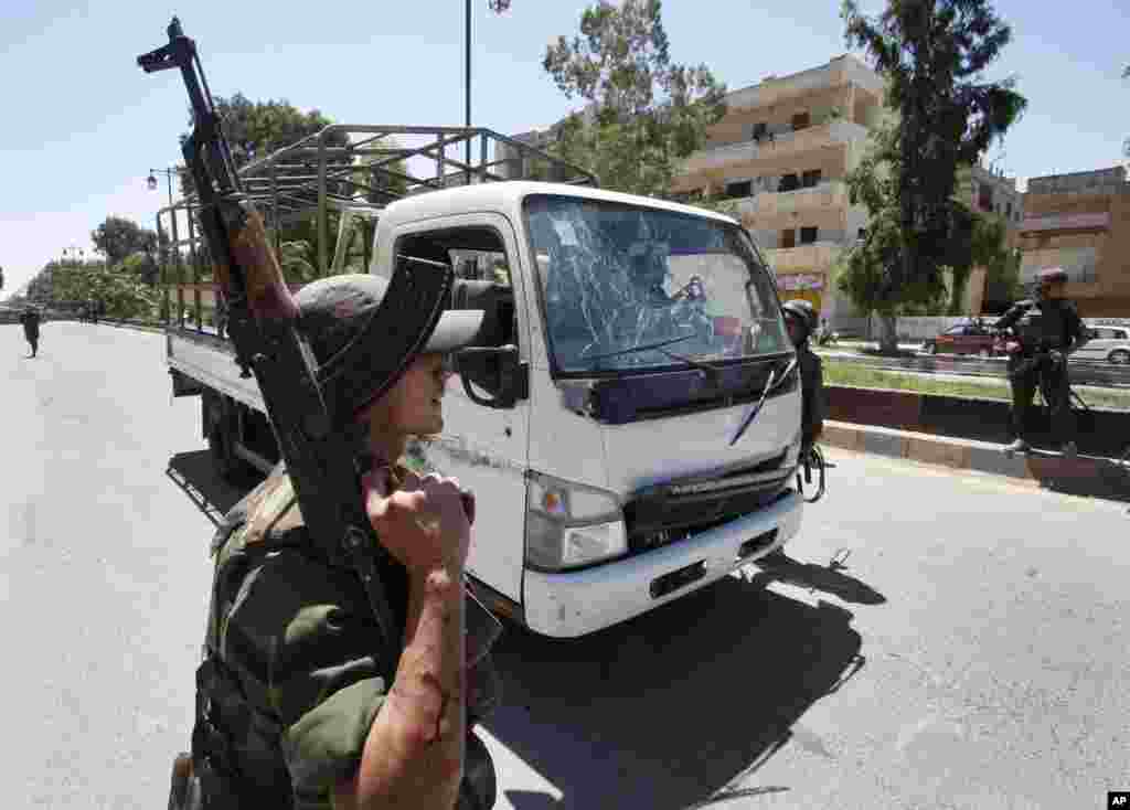 A Syrian army soldier secures the scene as he stands next to a military truck which was attacked by a roadside bomb.