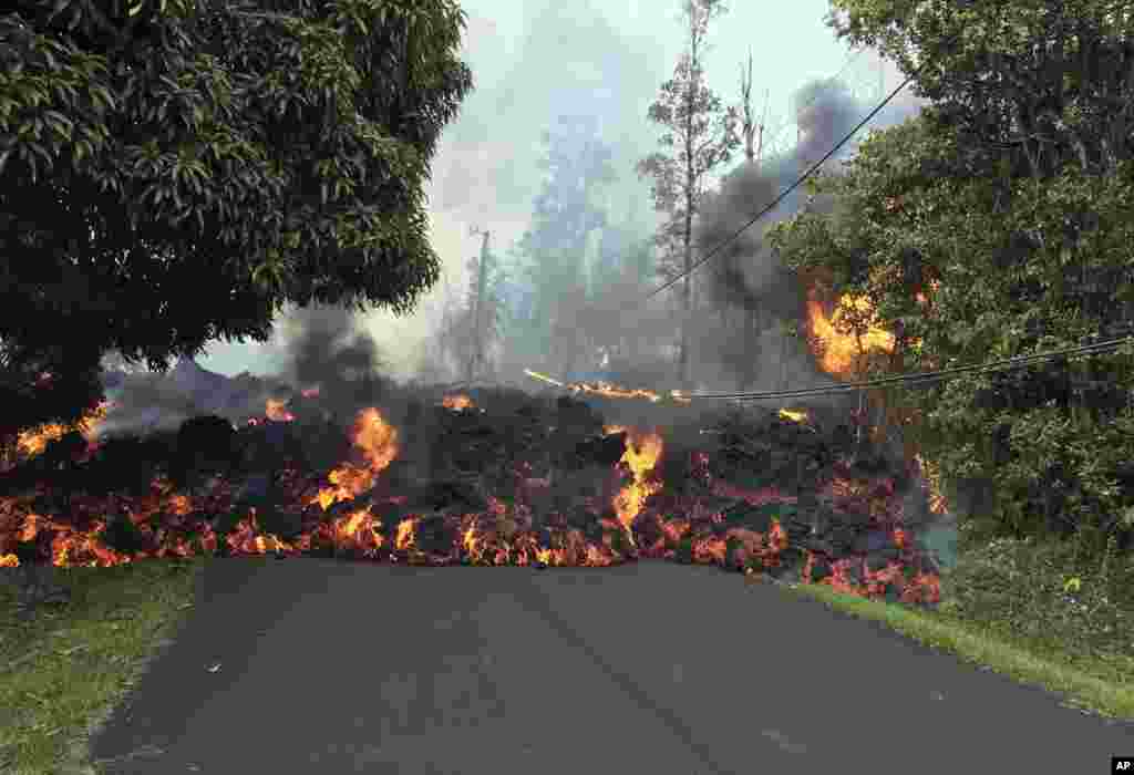 In this photo provided by the U.S. Geological Survey, a lava flow moves across Makamae Street in the Leilani Estates neighborhood near Pahoa on the island of Hawaii. The Kilauea volcano has destroyed more than 25 homes since it began shooting lava into the air last week, and residents who evacuated do not know how long they might be displaced. 