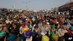 Para petani yang melancarkan aksi protes di perbatasan Delhi-Haryana, pinggiran New Delhi, India, mendengarkan pembicara di mimbar, Kamis, 17 Desember 2020. (Foto: AP)