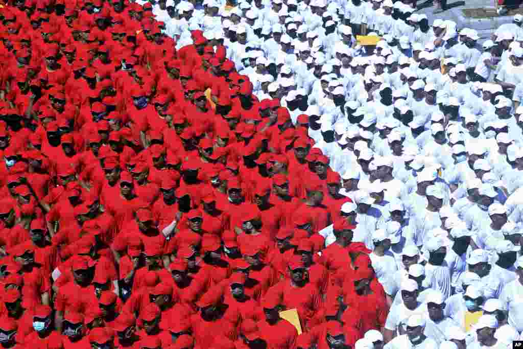 جریان یک رسم گذشت در شهر بالی اندونیزیا که شرکت کننده ها لباس و کلاۀ سرخ و سفید پوشیده اند.