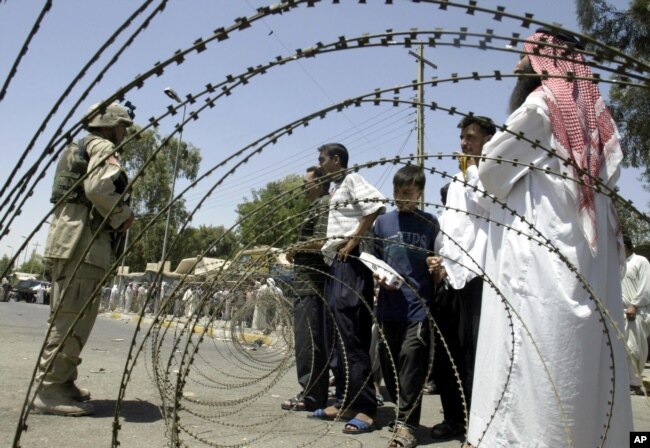 FILE - Iraqis try to persuade a U.S. soldier to enter the central bank in the northern city of Mosul during a protest, July 27, 2003.