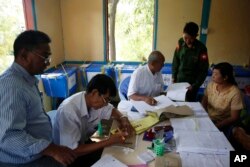 A Myanmar army officer, second right, checks whether his name is on the eligible voters list at a township Election Commission office in Mandalay, Myanmar, Nov. 5, 2015.