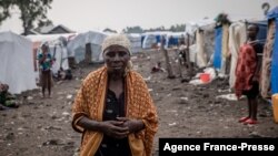 FILE - A woman walks at the Kayembe camp for dislaced persons, near Goma, Democratic Republic of Congo, Aug. 30, 2021.