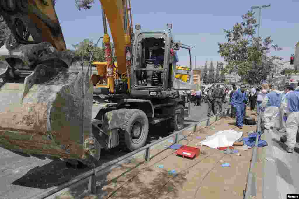 The body of a Palestinian driver of a construction vehicle lies covered at the scene of a an attack. He was suspected of overrturning a bus with a heavy construction vehicle, in Jerusalem, Aug. 4, 2014.