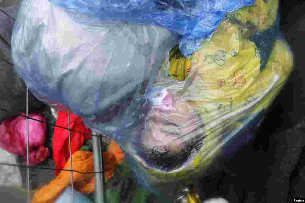 A migrant's child sleeps as it is seen in a rain cover at the border crossing from Slovenia in Trnovec, Croatia October 19, 2015. 