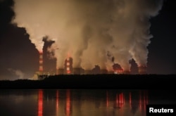 FILE - Smoke and steam billows from Belchatow Power Station, Europe's largest coal-fired power plant, operated by PGE Group, at night near Belchatow, Poland, Dec. 5, 2018.