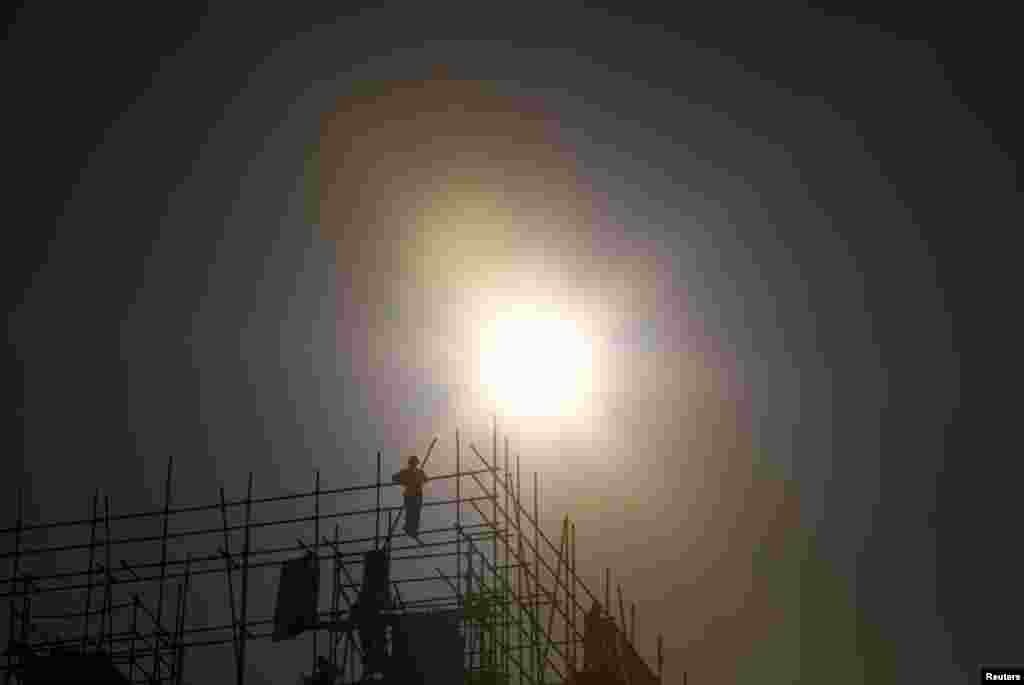 A laborer works on top of scaffolding at a construction site in Beijing, China.