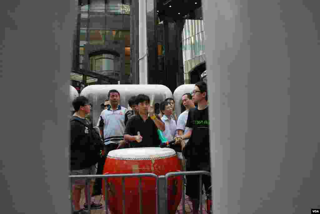 示威人士在水马阵隔着的示威区内击鼓，喻意为李旺阳击鼓鸣冤
