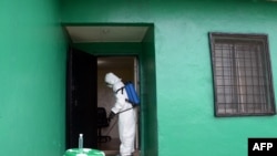 A health worker, wearing a protective suit, disinfects a house during an Ebola prevention drill at the port in Monrovia, Liberia, Aug. 29, 2014.