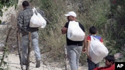 Syrian refugees carry food supplies donated by Turkish villagers across the border to fellow Syrians still stuck in Syria, near the village of Guvecci, Turkey, on the border with Syria, June 13, 2011