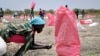 Seorang perempuan Sudan mengumpulkan biji sorgum yang tercecer di tanah dari bahan pangan yang dijatuhkan dari udara oleh Program Pangan Dunia (WFP) di kota Kandak, Sudan Selatan, 2 Mei 2018. (AP Photo/Sam Mednick)