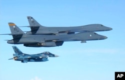 In this photo released by Japan Air Self Defense Force, U.S. Air Force B-1B bombers, top, fly with a Japan Air Self Defense Force F-2 fighter jet over Japan's southern island of Kyushu, just south of the Korean Peninsula, during a Japan-U.S. joint exercise.
