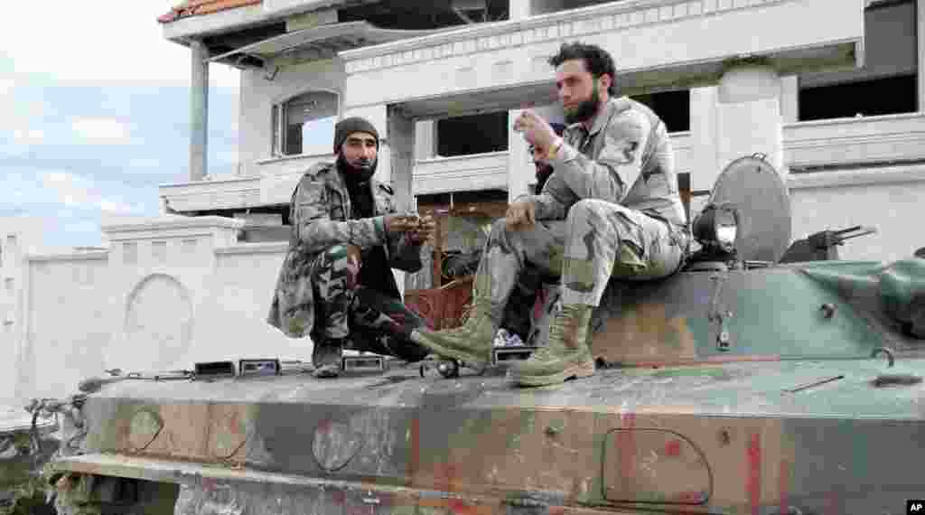 Free Syrian Army fighters eat atop an armored personnel carrier that belonged to forces loyal to president Bashar al Assad, at the police academy in Aleppo after capturing it, March 4, 2013. 