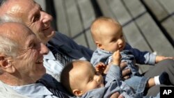 In this Saturday, June 18, 2005 file photo, identical twins Alf, left, and Sven Fehnhanhn, left background, 79, from Kassel, Germany, pose along with seven-month-old Luis Carl, right, and Albert Frank Millgramm, right background at a twins' meeting in Berlin.