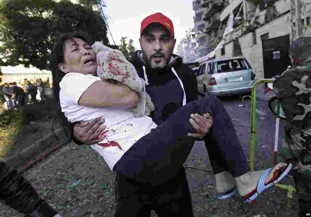 A man carries an injured domestic worker after explosions near the Iranian embassy in Beirut, Nov. 19, 2013.