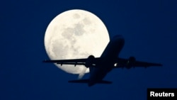 FILE - A passenger aircraft is silhouetted against the rising moon in New Delhi, May 7, 2009. 