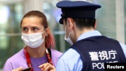 La sprinteuse biélorusse Krystsina Tsimanouskaya discute avec des policiers à l'aéroport international de Haneda à Tokyo, au Japon, le 1er août 2021.