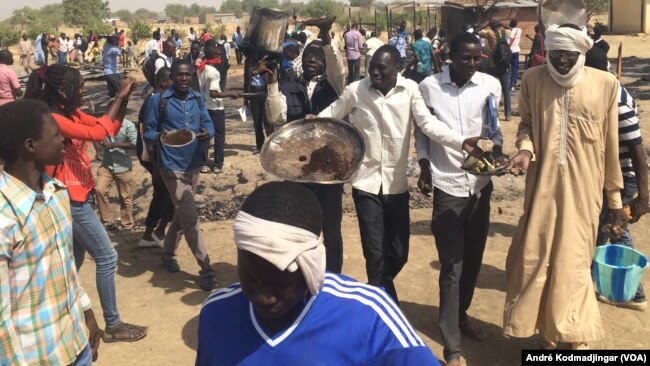 Les étudiants sur les cendres de leur restaurant brûlés par la police entonnant l'hymne national, à N'Djamena, Tchad, le 14 février 2017. (VOA/André Kodmadjingar)
