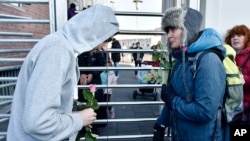 A woman gives a flower to a migrant at the fence of a refugee home in Cologne, Germany, Jan. 22, 2016.