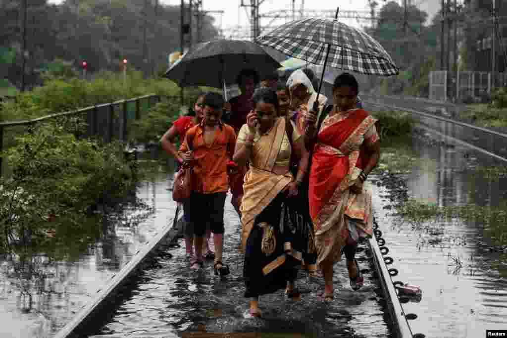 Commuters walk on waterlogged railway tracks after getting off a stalled train during heavy monsoon rains in Mumbai, India.