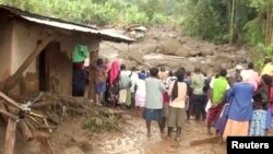 Residents watch flood waters pass through destroyed homes, after a landslide in Bududa, Uganda, in this still image taken from video, Oct. 12, 2018.