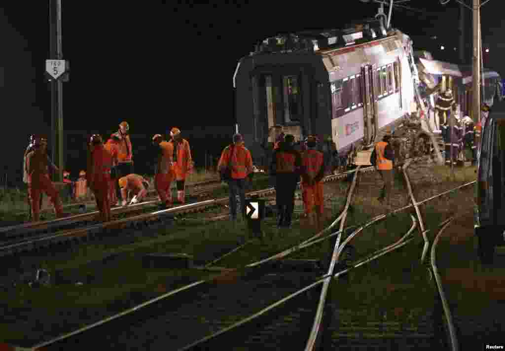 Swiss Federal Railways staff inspect the rails after removing carriages after a collision between two trains near Granges-pres-Marnand, Switzerland, July 29, 2013. 