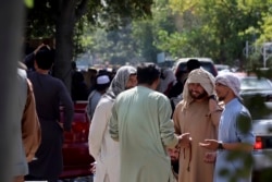 Afghans wait for hours to try to withdraw money, in front of Kabul Bank, in Kabul, Afghanistan, Saturday, Aug. 28, 2021.