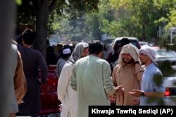 Afghans wait for hours to try to withdraw money, in front of Kabul Bank, in Kabul, Afghanistan, Saturday, Aug. 28, 2021.