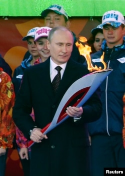 Russian President Vladimir Putin holds a lighted Olympic torch during a ceremony to mark the start of the Sochi 2014 Winter Olympic torch relay in Moscow, Oct. 6, 2013.