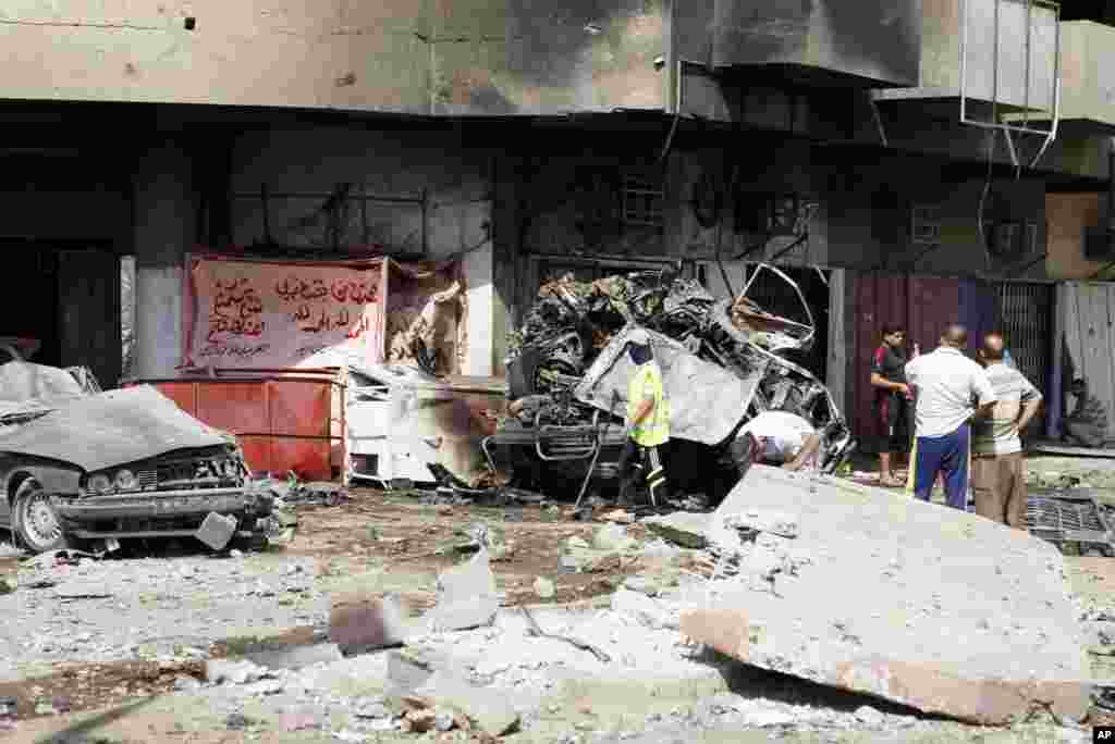 People inspect the scene of a car bomb attack in the Karrada neighborhood of Baghdad, Iraq, June 13, 2012.