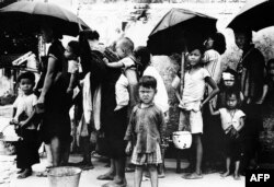1962年5月拍摄的照片显示，逃离中国大饥荒的难民在香港排队领取食物。