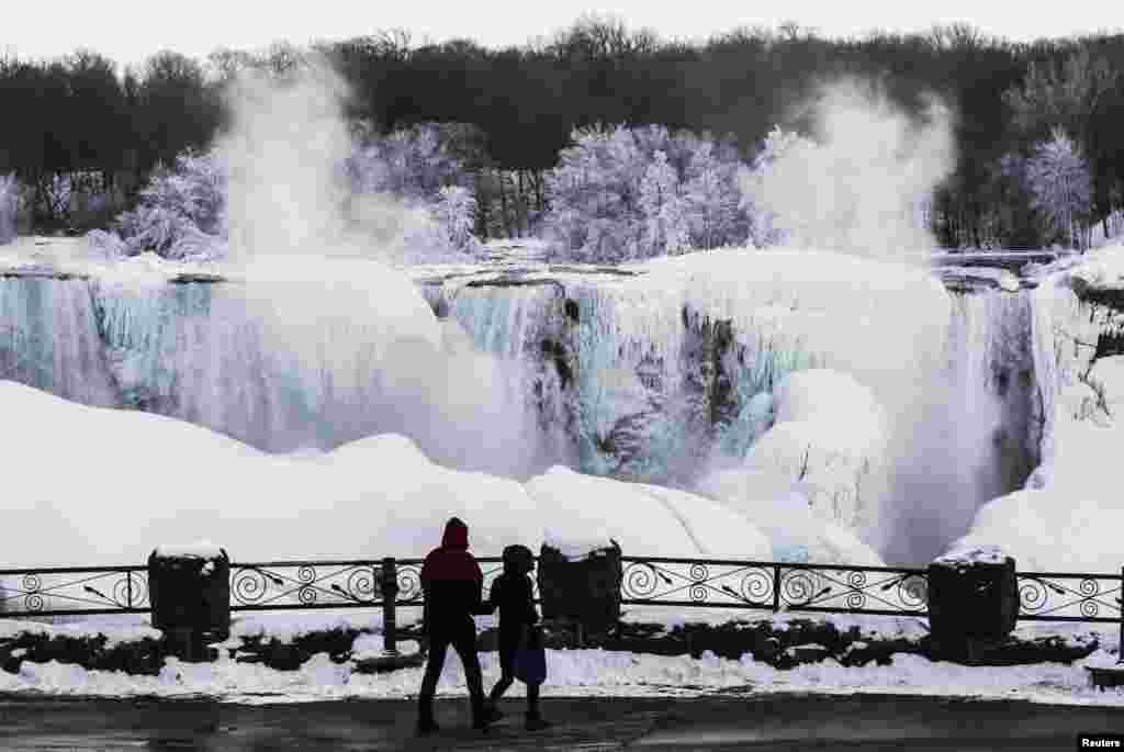 A couple looks out over the partially frozen American side of the Niagara Falls during sub-freezing temperatures in Niagara Falls, Ontario, Canada, Mar. 3, 2014. 