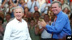 FILE - President George W. Bush, left, is introduced by his brother Florida Governor Jeb Bush (R) at a campaign rally, in Niceville, Florida, August 2004.