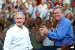 FILE - President George W. Bush, left, is introduced by his brother Florida Governor Jeb Bush, right, at a campaign rally, in Niceville, Florida, August 2004.