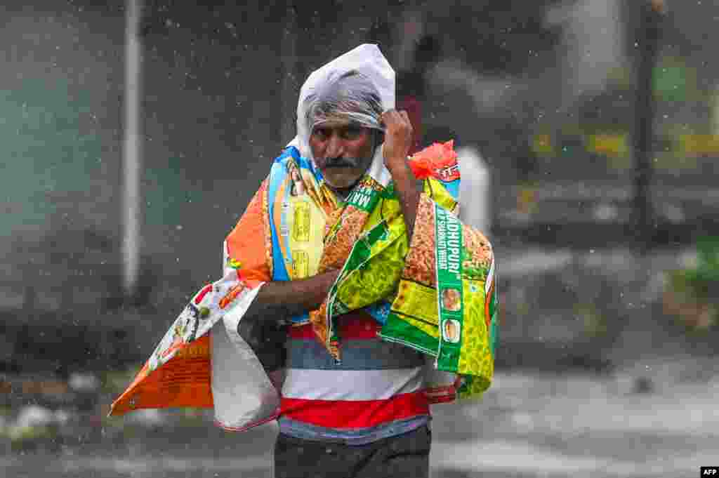 A man covers himself with plastics as he walks along a street in Amreli, after Cyclone Tauktae hit the west coast of India with powerful winds and driving rain, leaving at least 20 people dead.