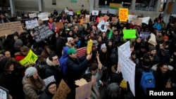 Protes menentang larangan imigrasi Donald Trump di luar Terminal 4 di Bandar Udara John F. Kennedy di Queens, New York (28/1). (Reuters/Andrew Kelly)