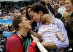 FILE - Michael Phelps celebrates winning his gold medal in the men's 200-meter butterfly with his then-fiance, Nicole Johnson, and baby, Boomer, during the swimming competitions on Aug. 9 at the 2016 Summer Games.