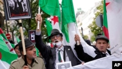 FILE - Demonstrators with Algerian flags chant slogans in Paris, Oct. 17, 2021. A tribute march was organized for the 60th anniversary of the police crackdown on a protest by Algerians in Paris, during the last year of their nation's independence war with its colonial power.