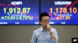 A currency trader walks by the screens showing the Korea Composite Stock Price Index (KOSPI), left, and the foreign exchange rate between US dollar and South Korean won at the foreign exchange dealing room in Seoul June 24, 2016. (AP)