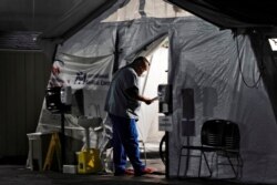 Seorang nakes memeriksa pasien di dalam tenda khusus di luar ruang gawat darurat Rumah Sakit Komunitas Huntington Park, saat kasus positif COVID-19 melonjak di Huntington Park, California, 29 Desember 2020. (Foto: dok).