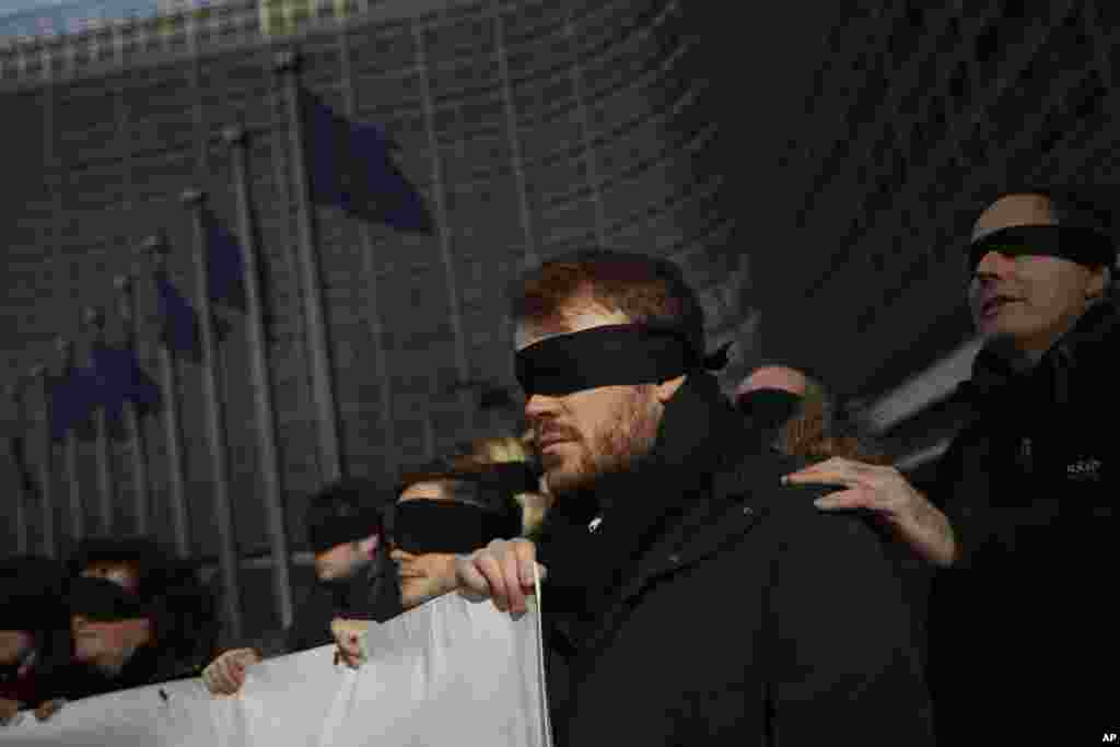 Anti-Brexit activists wearing cloth covers over their eyes protest outside the European Commission headquarters in Brussels, Belgium, during a meeting between EC President Jean-Claude Juncker and British Prime Minister Theresa May.