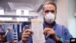 Novinar Brian Fuss pokazuje informacije o svom testu na COVID-19 nakon što se testirao u ambulanti Bijele kuće prije konferencije za novinare predsjednika Trumpa, 9. aprila 2020.