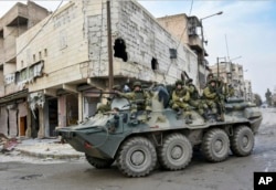 FILE - This undated handout photo released by the Russian Defense Ministry claims to show Russian Military engineers driving in their armored personnel carrier to operate in Aleppo, Syria.