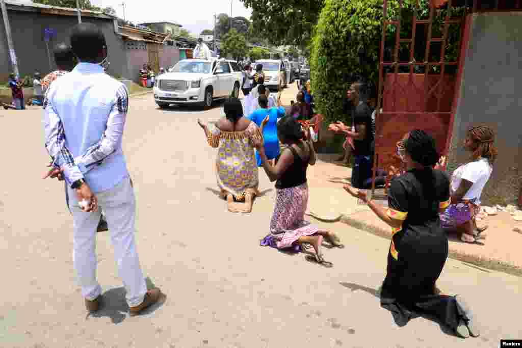 Catholics kneel as Father Norbert Abekan of the Notre Dame de la Tendresse de la Riviera travels around the streets to pray in Abidjan, Ivory Coast.